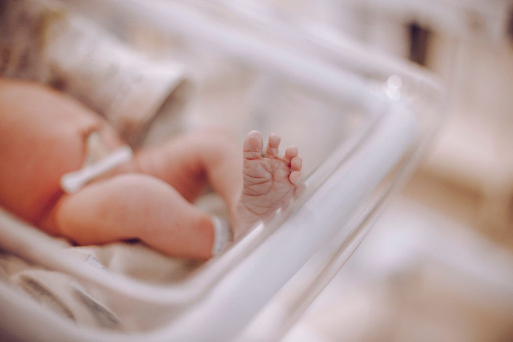 A newborn's foot in a hospital bassinet.