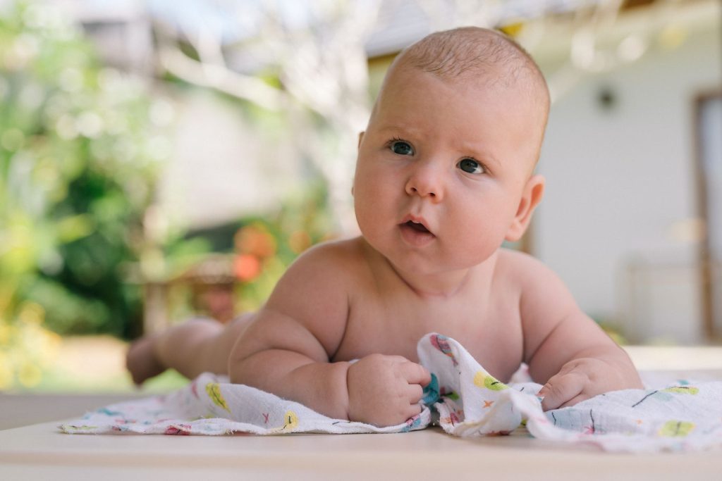 A baby on a blanket during tummy time.