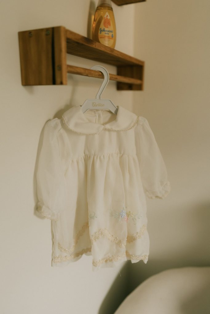 A white vintage baby gown hanging in soft light.