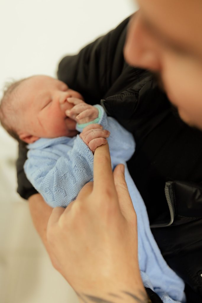 A newborn's tiny hand holding a grown-up's finger.