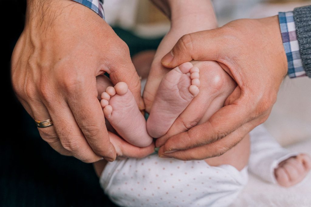 A parent's hands gently holding a baby's feet.