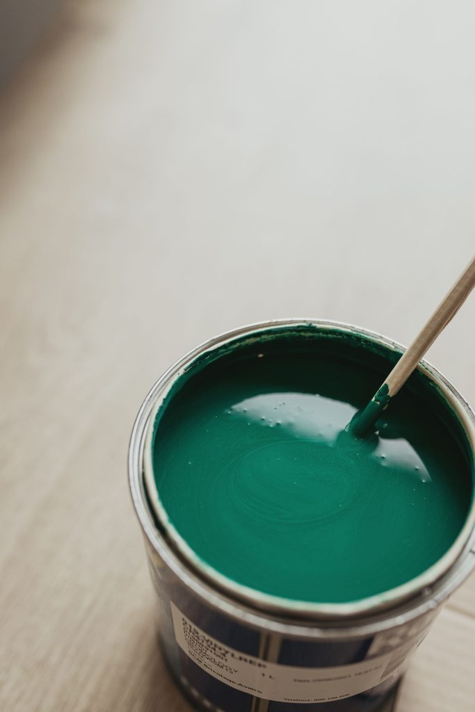An open can of green paint being stirred.