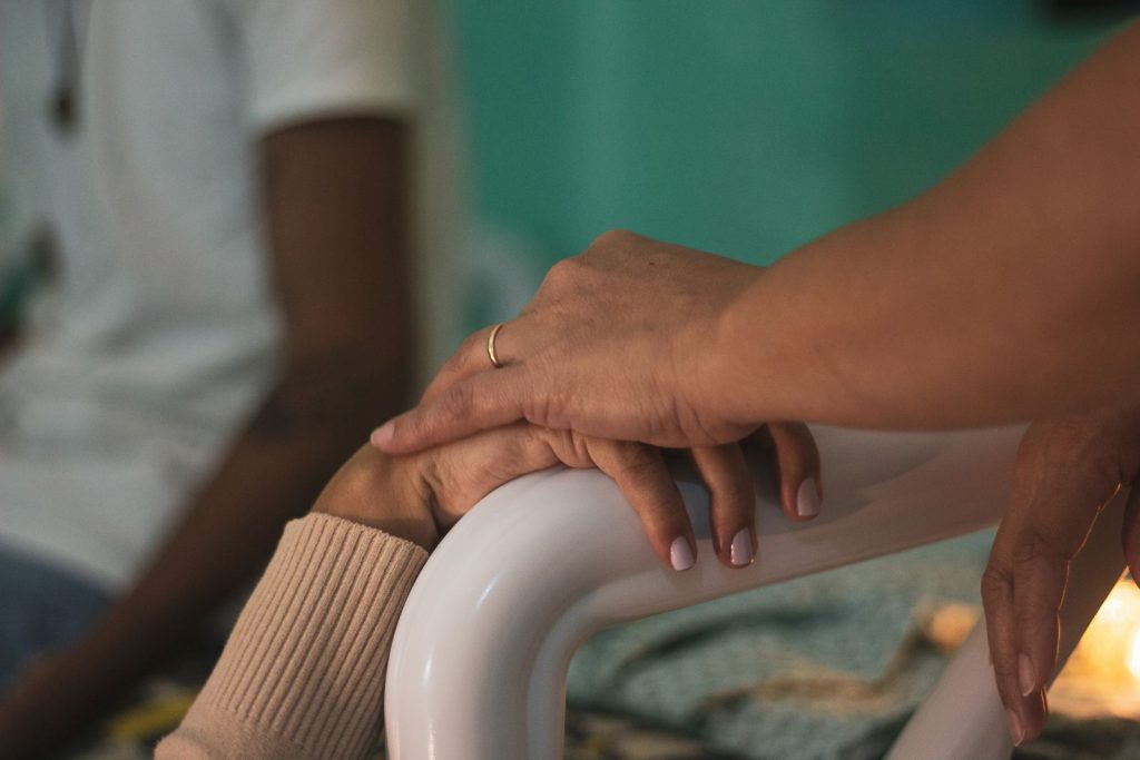 Two hands holding each other in a hospital room.