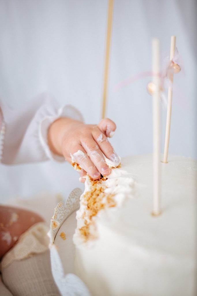 A baby's hand touching a birthday cake.