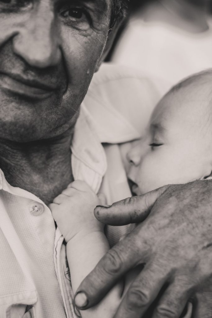 Black and white photo of a grandfather holding a sleeping baby.