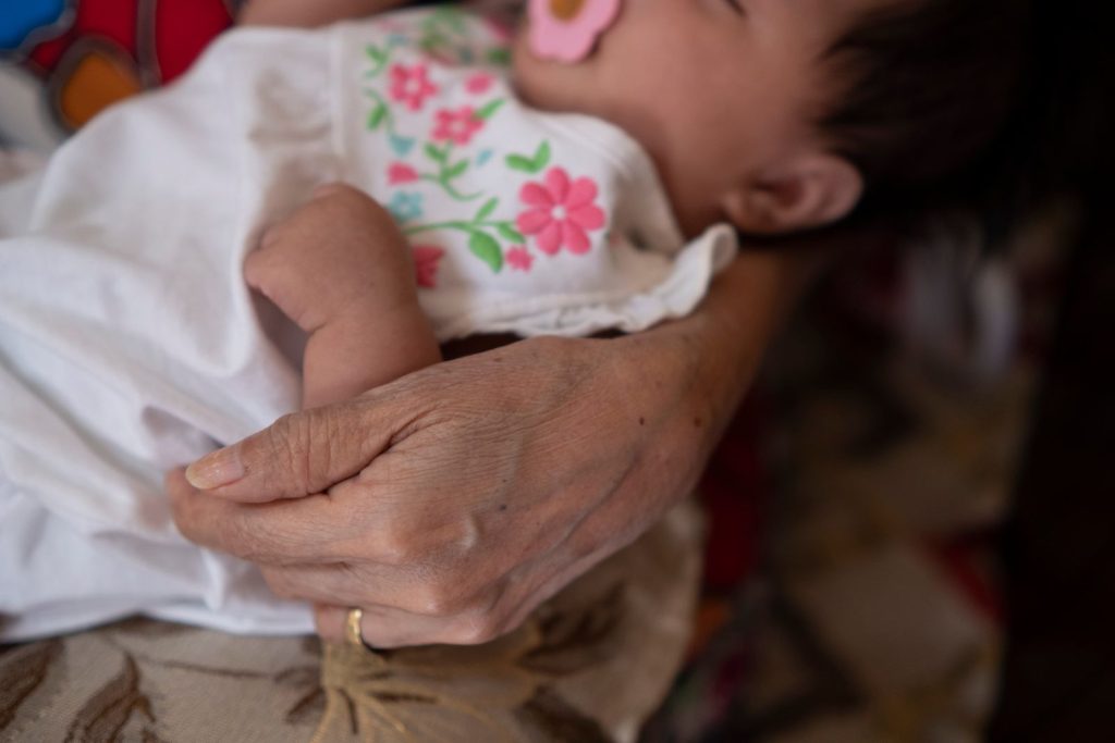 A grandmother holding a sleeping baby.