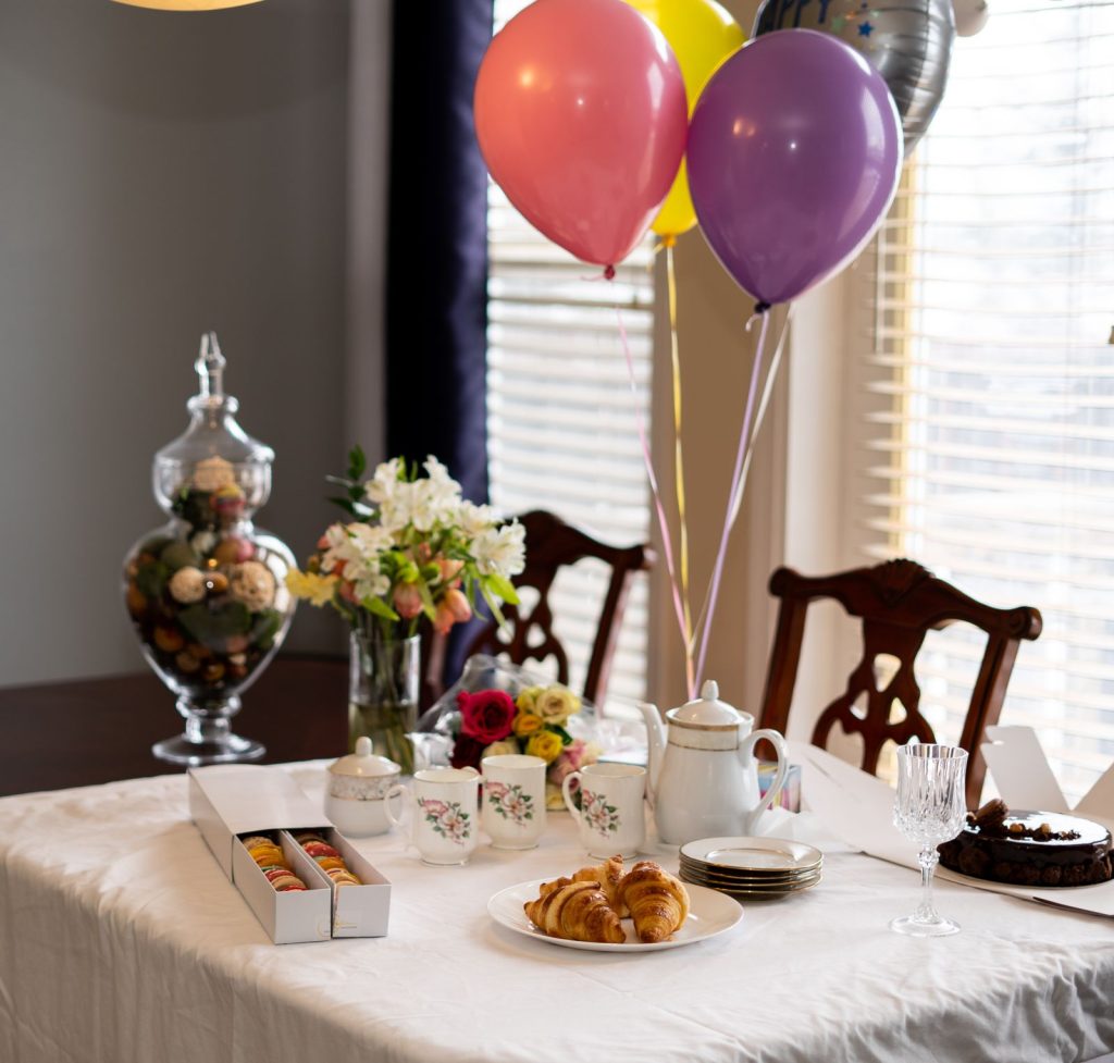 A party table set with flowers, pastries and a tea set.