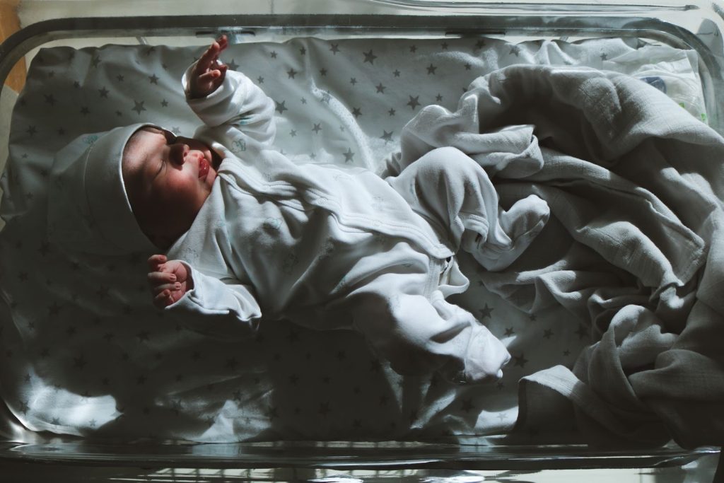 A newborn sleeping in a hospital bassinet, seen from above.